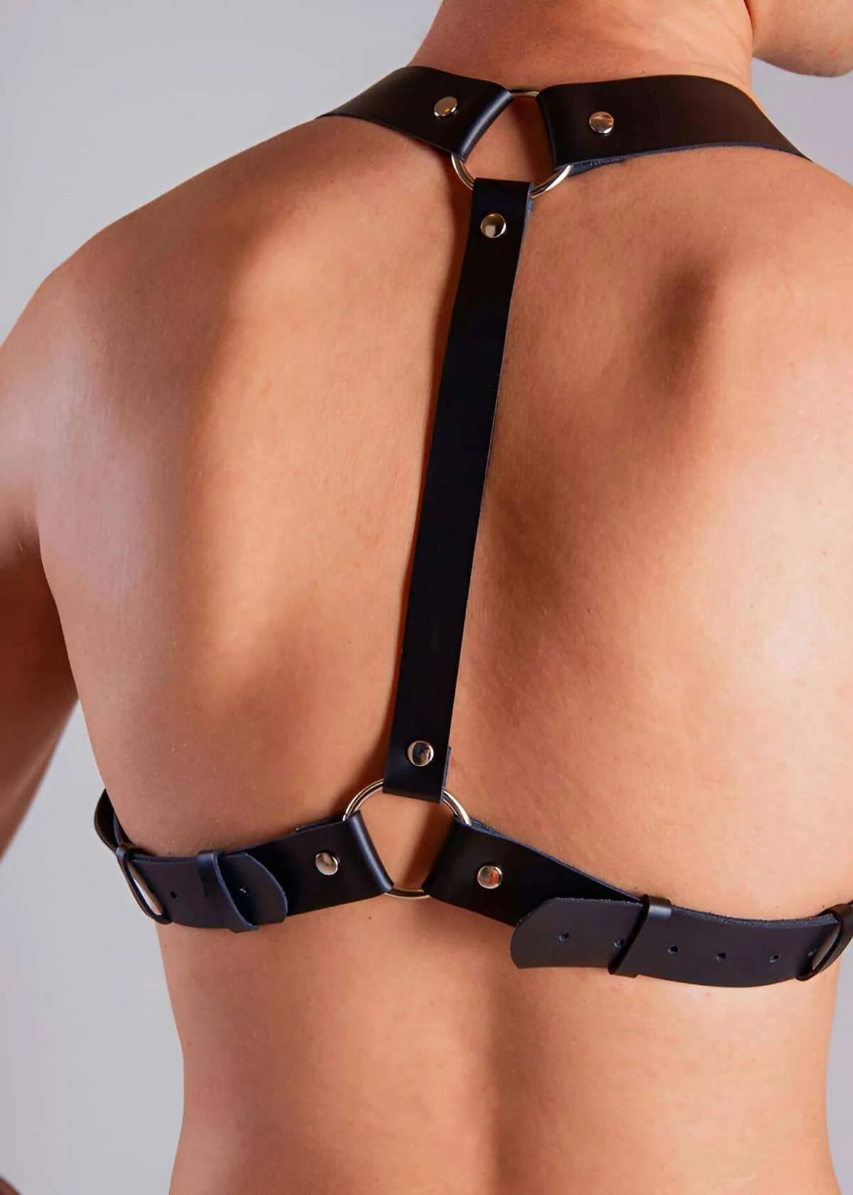 Erkek gövdesinde gümüş O-halkalar ve ayarlanabilir tokalarla siyah suni deri arka vücut harness arka görünüm
