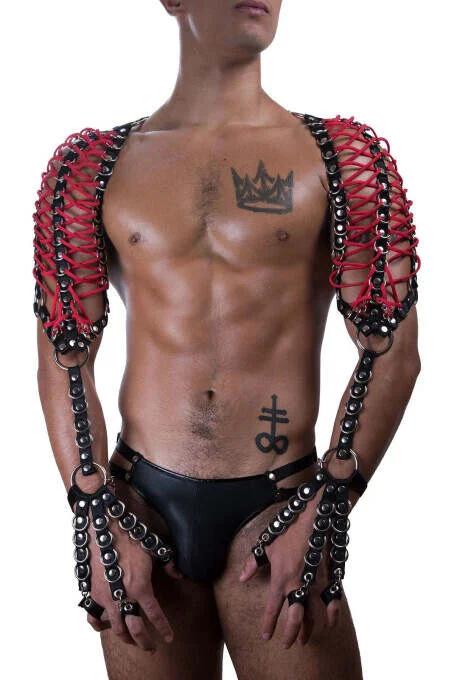 Erkek model tarafından giyilen kırmızı suni deri omuz harness'ı, siyah zincir kafes paneller, gümüş O-halkalar, bilek kelepçeleri