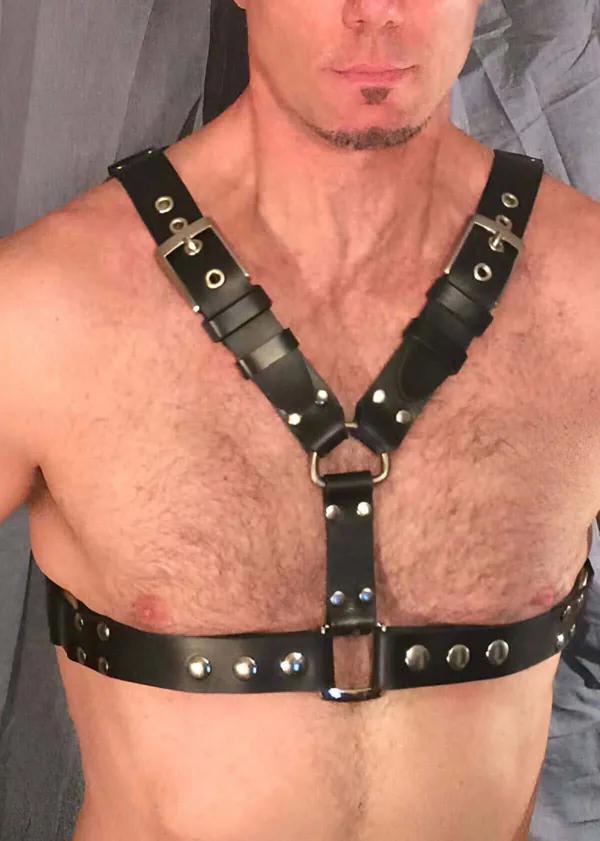 Bir erkek tarafından giyilen gümüş tokalar ve kubbeli perçinler, merkez D-halkalı Y-askı tasarımlı siyah suni deri göğüs harness
