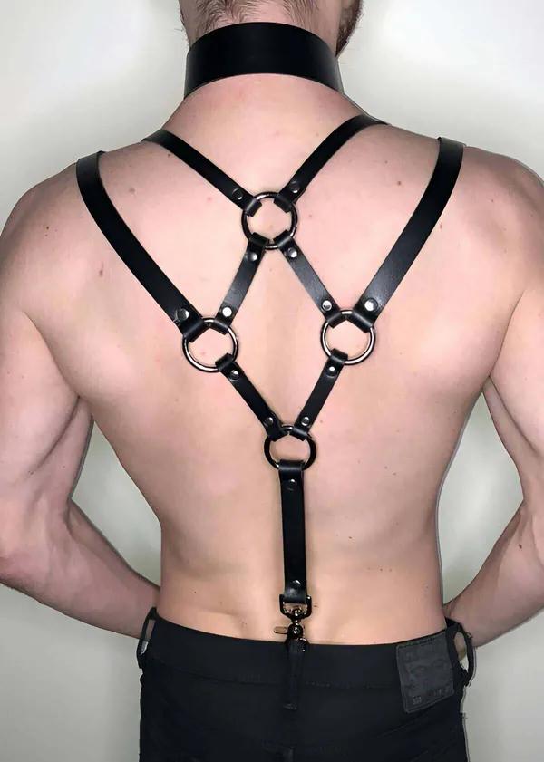 Eşleşen geniş boyunlukla giyilmiş dört gümüş O-halka ve X-çapraz bant tasarımlı siyah suni deri sırt harness