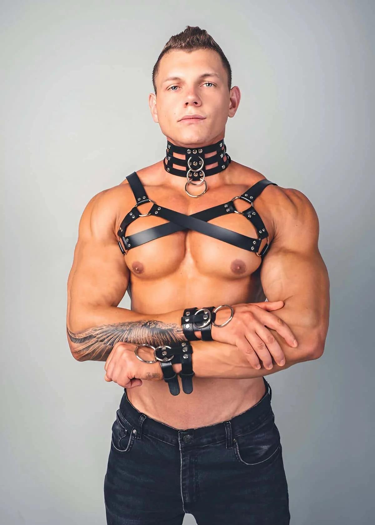 Erkek modelde geniş zımbalı boyunluk ve bilek kelepçeli siyah suni deri X-çapraz göğüs harness